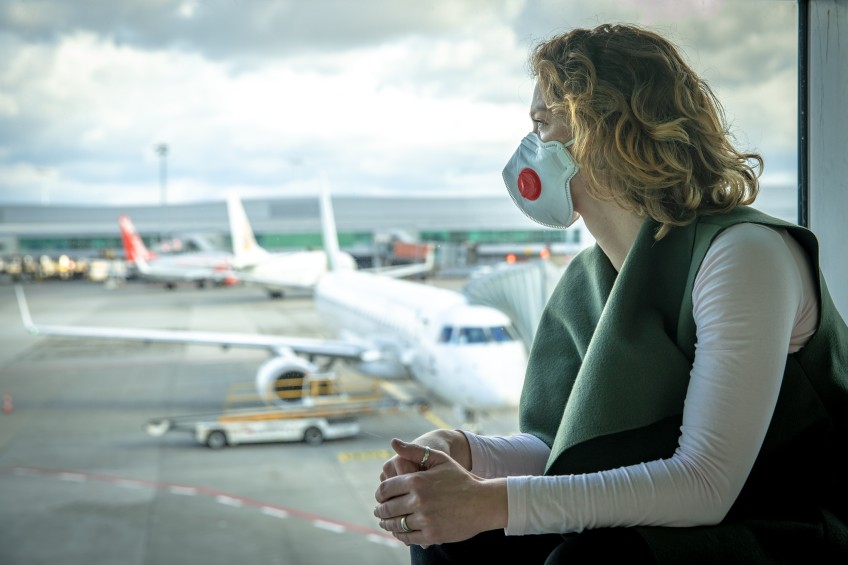 Pressemitteilung Reisen in Corona-Zeiten - Frau mit Maske am Flughafen